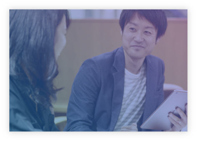 画像：男性写真が女性写真に話をしている様子。手にはタブレットを持っている。